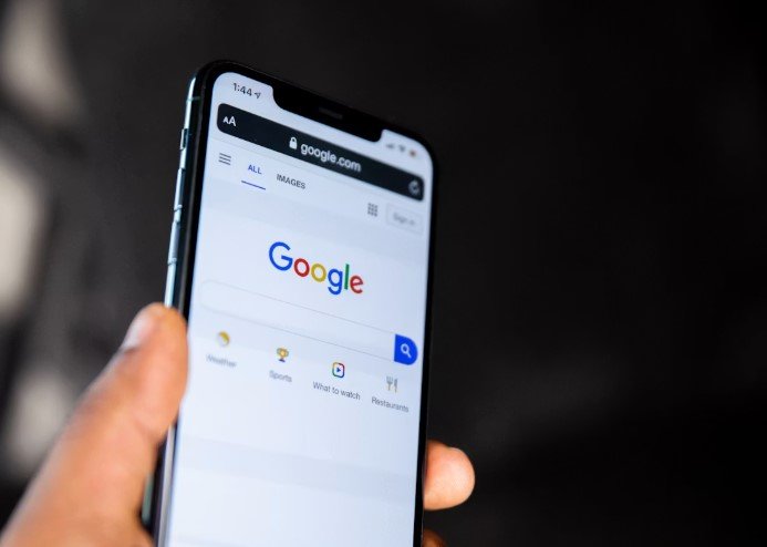 Hand hält ein Smartphone mit geöffneter Google-Suche
